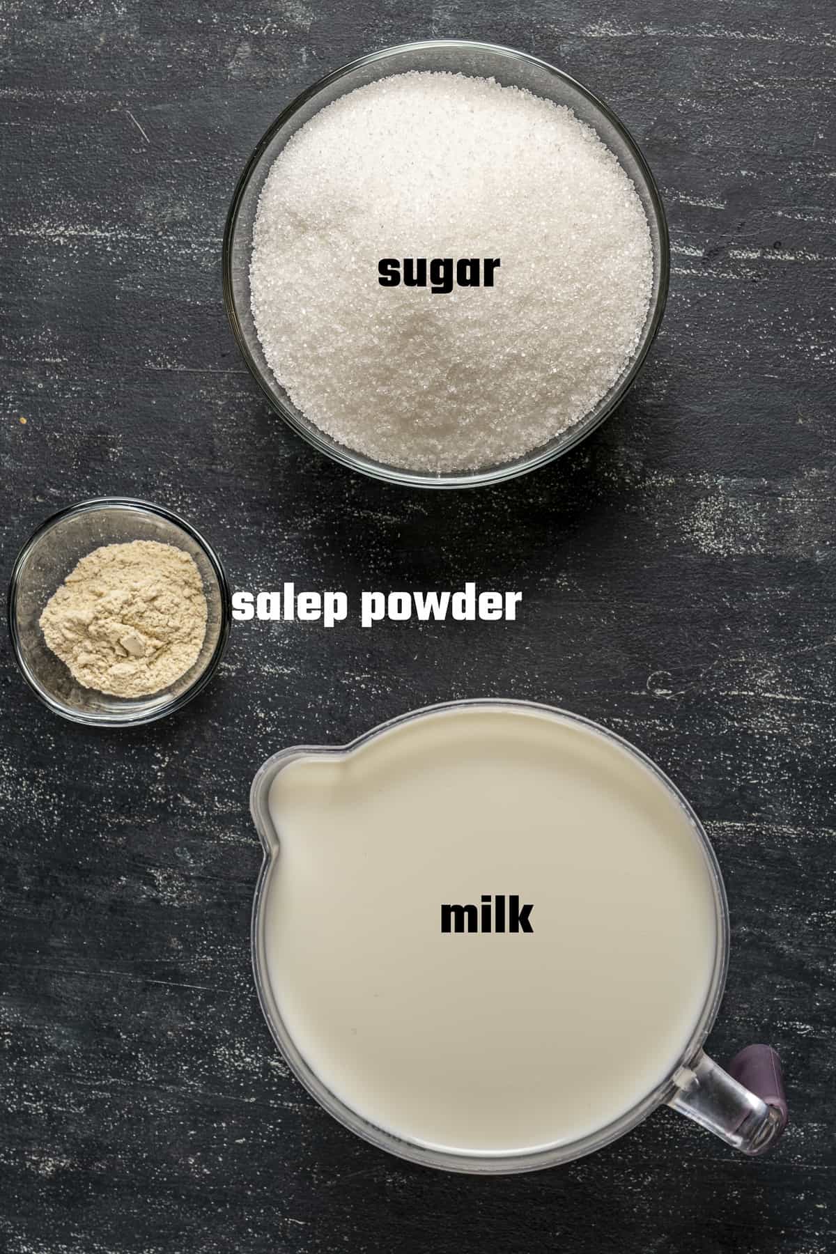 Sugar, milk and salep powder on a dark background.