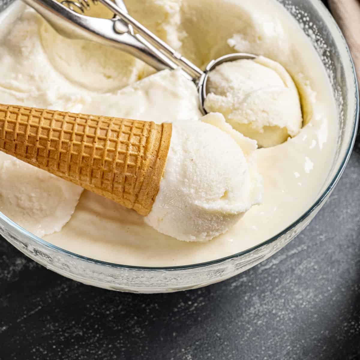 Turkish ice cream in a large bowl, a cone and a scoop inside it.