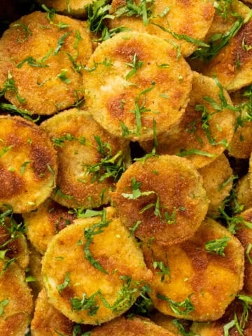 Golden fried zucchini chips garnished with parsley.