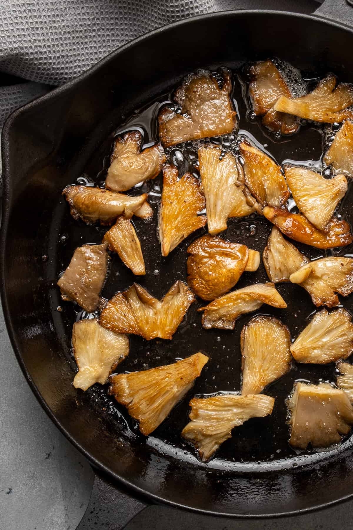 Oyster mushrooms cooking in a cast iron skillet.