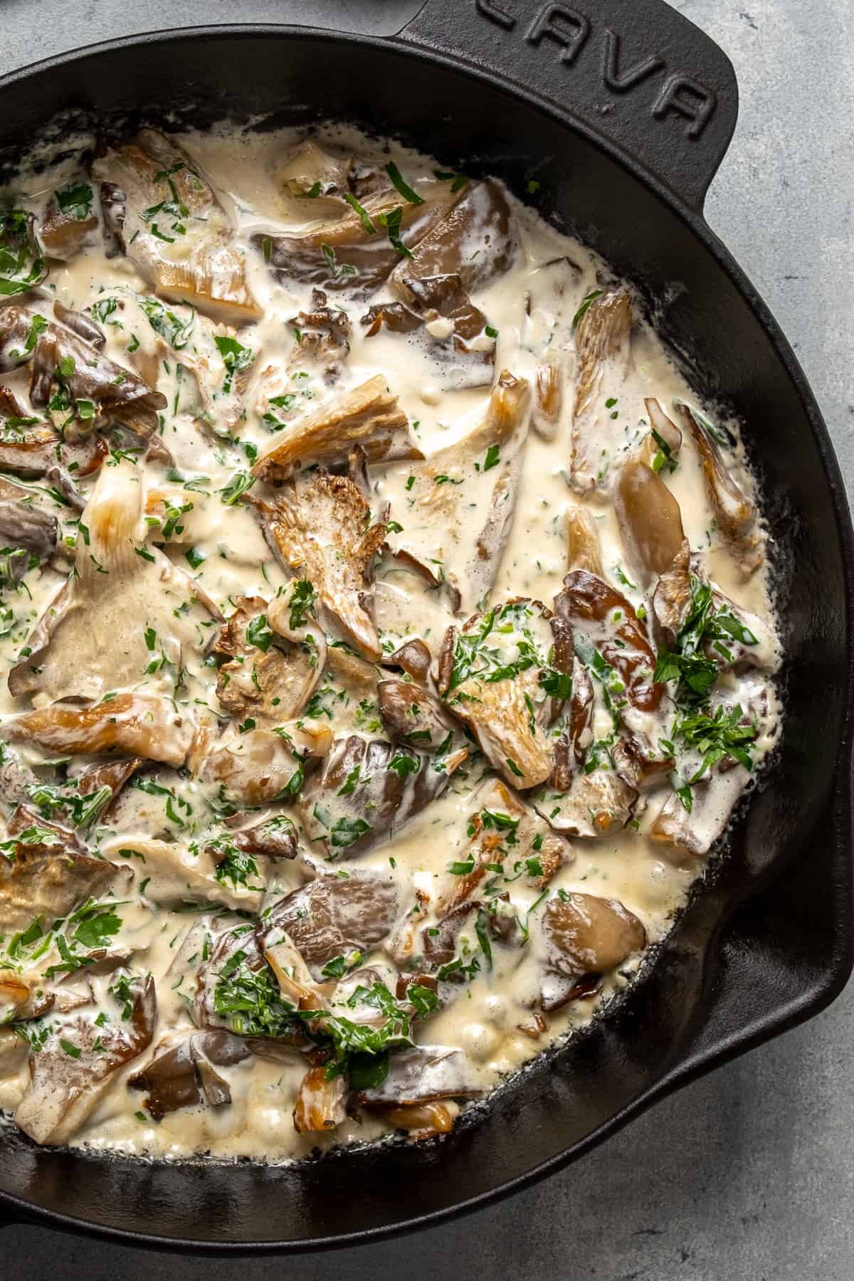 Creamy oyster mushroom sauce with parsley in a cast iron skillet.