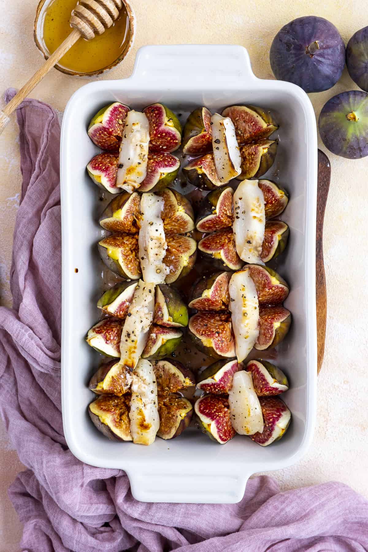 Baked figs stuffed with goat cheese in a white baking pan.