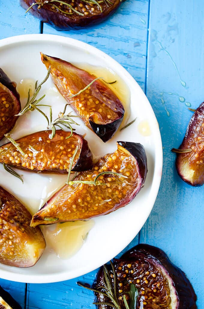 Roasted figs with honey and rosemary on a white plate