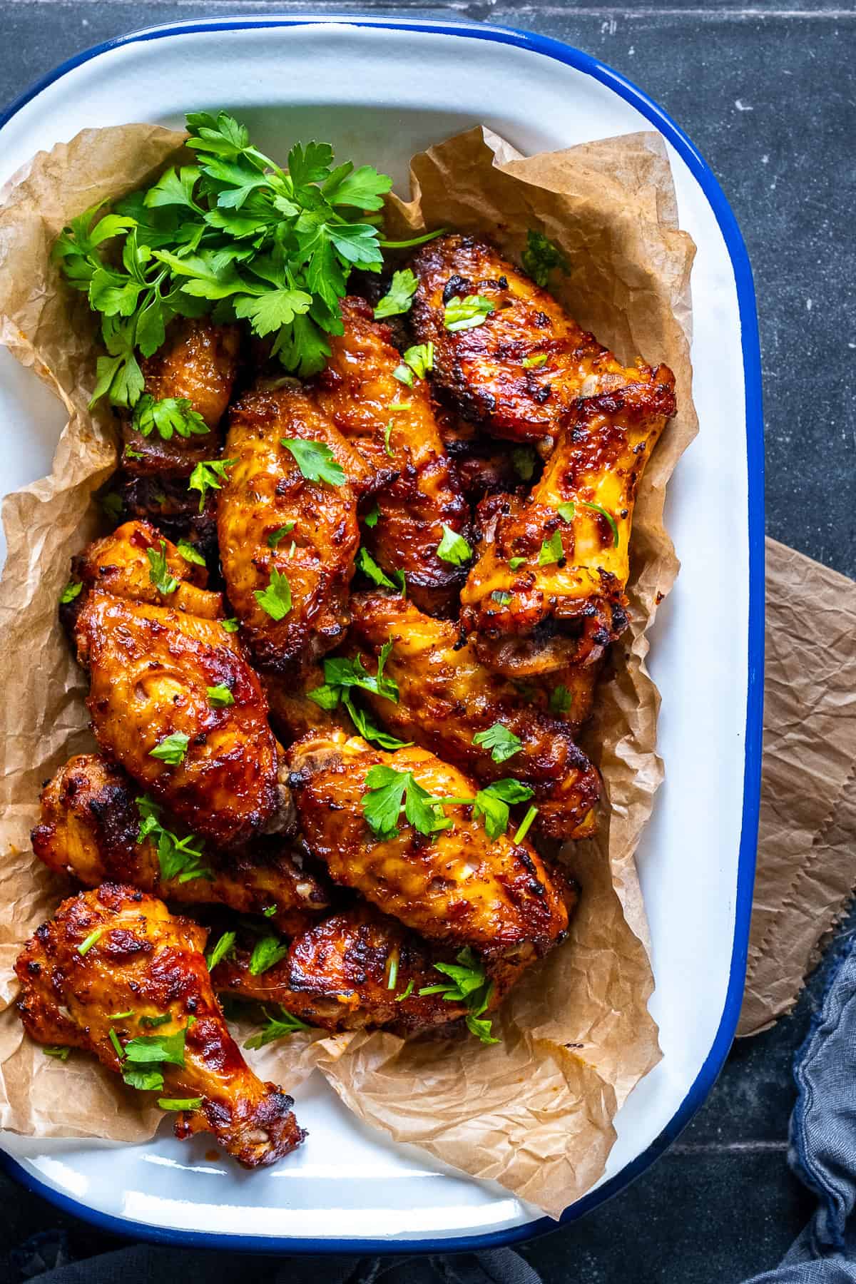 Juicy, golden Turkish-style chicken wings served with parsley on parchment in a rustic tray.
