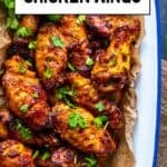 Juicy, golden Turkish-style chicken wings served with parsley on parchment in a rustic tray.