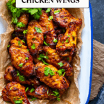 Juicy, golden Turkish-style chicken wings served with parsley on parchment in a rustic tray.