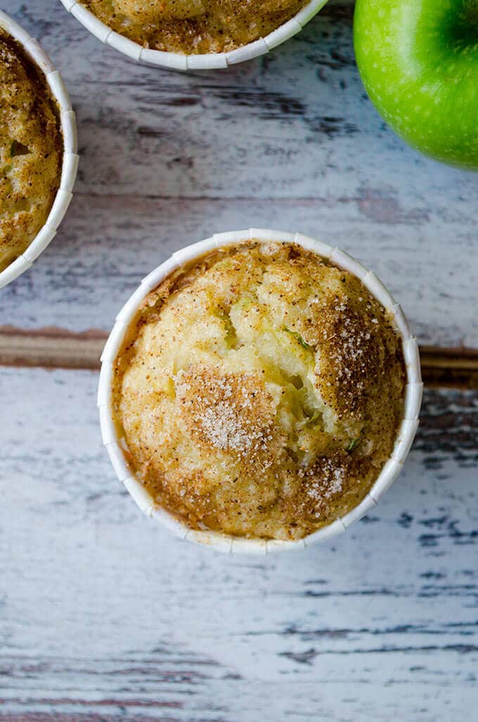 Zucchini Apple Cinnamon Muffins with cinnamon sugar topping. Wonderfully moist thanks to zucchini, applesauce, grated apple and yogurt. Perfect on the go breakfast in fall! #zucchinirecipes #applecinnamonmuffins #fallbaking #zucchinimuffins Zucchini Apple Cinnamon Muffins on a white backdrop
