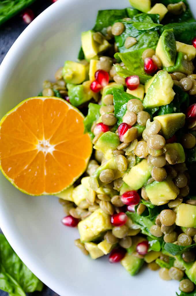 Vegan Lentil Salad with spinach, mandarin, avocado and pomegranate in a white bowl