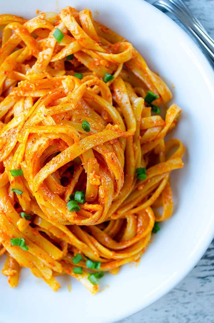 Fettuccine with creamy tomato sauce, slightly flavored with parmesan. This is the weeknight dinner everyone in my family asks for. Every single day! #fettuccine #creamytomatopasta #tomatosauce #pastawithtomatosauce #easydinnerfortoddlers Tomato sauce pasta with parmesan in a white pasta bowl.