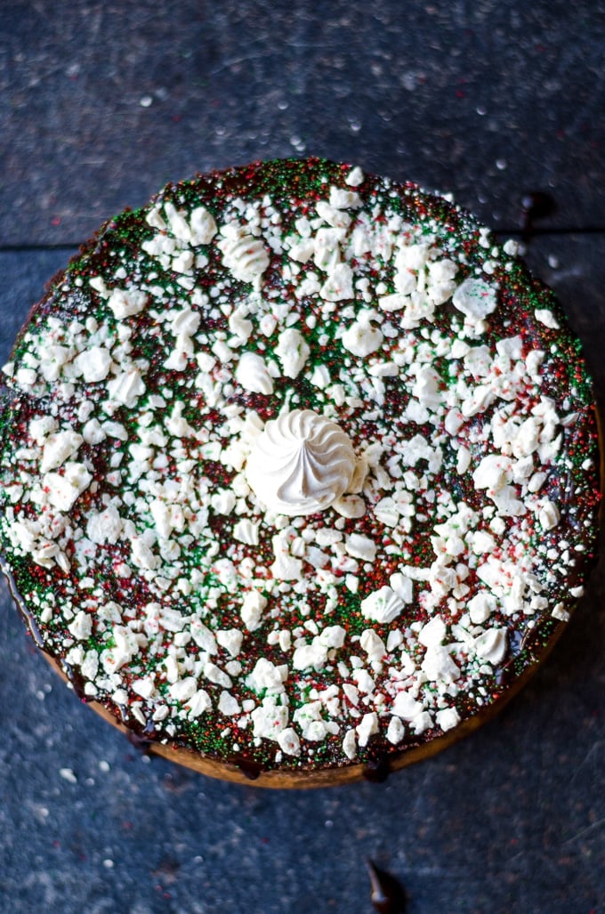 Chocolate cake made with beets and topped with sprinkles and crumbled meringue on a round cake stand.