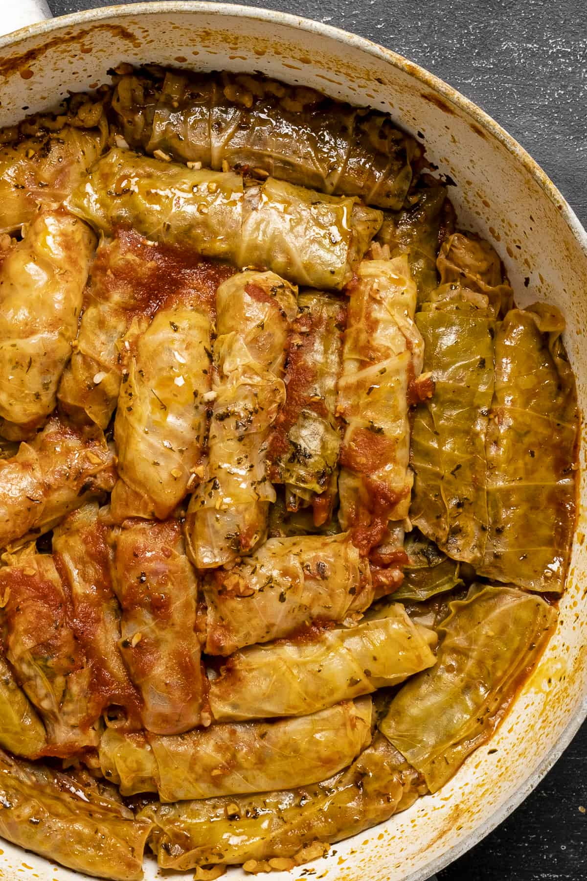 Cabbage rolls cooked with tomato sauce in a white pan.