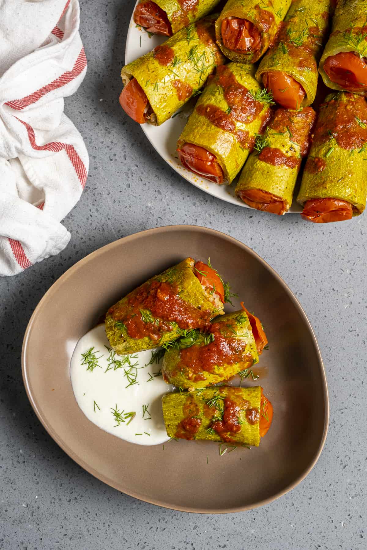 Kabak dolma on a brown plate served with tomato sauce on it and yogurt on the side.