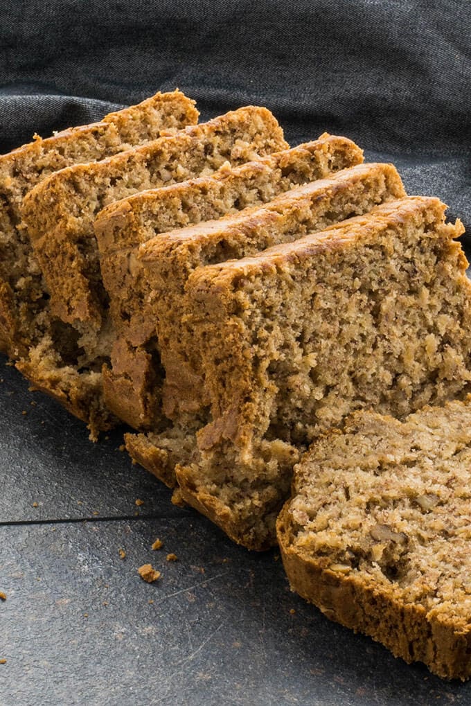 Vegan Banana Bread with walnuts sliced on a dark backdrop