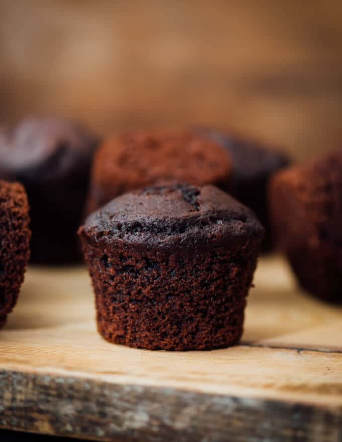 These Buttermilk Chocolate Muffins are perfectly moist, tender and chocolatey. You will feel like you’re eating brownies in each bite. These make a wonderful grab and go breakfast or a quick after school snack. #chocolatemuffins #muffinrecipe #buttermilkmuffins Buttermilk Chocolate Muffins on a wooden board