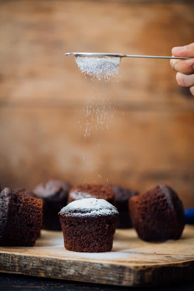 Sifting powdered sugar on chocolate muffins with buttermilk