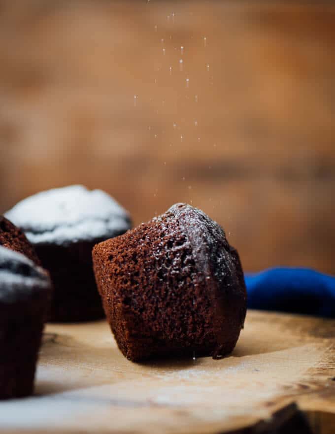 These Buttermilk Chocolate Muffins are perfectly moist, tender and chocolatey. You will feel like you’re eating brownies in each bite. These make a wonderful grab and go breakfast or a quick after school snack. #chocolatemuffins #muffinrecipe #buttermilkmuffins Dusting powdered sugar over chocolate muffins made with buttermilk
