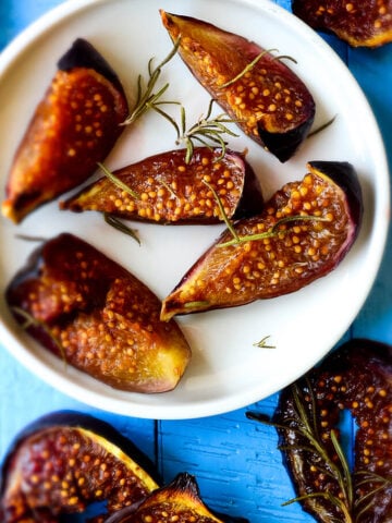 Roasted figs with rosemary and honey on white plate