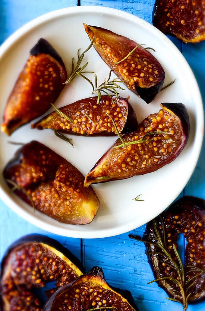 Roasted figs with rosemary and honey on white plate