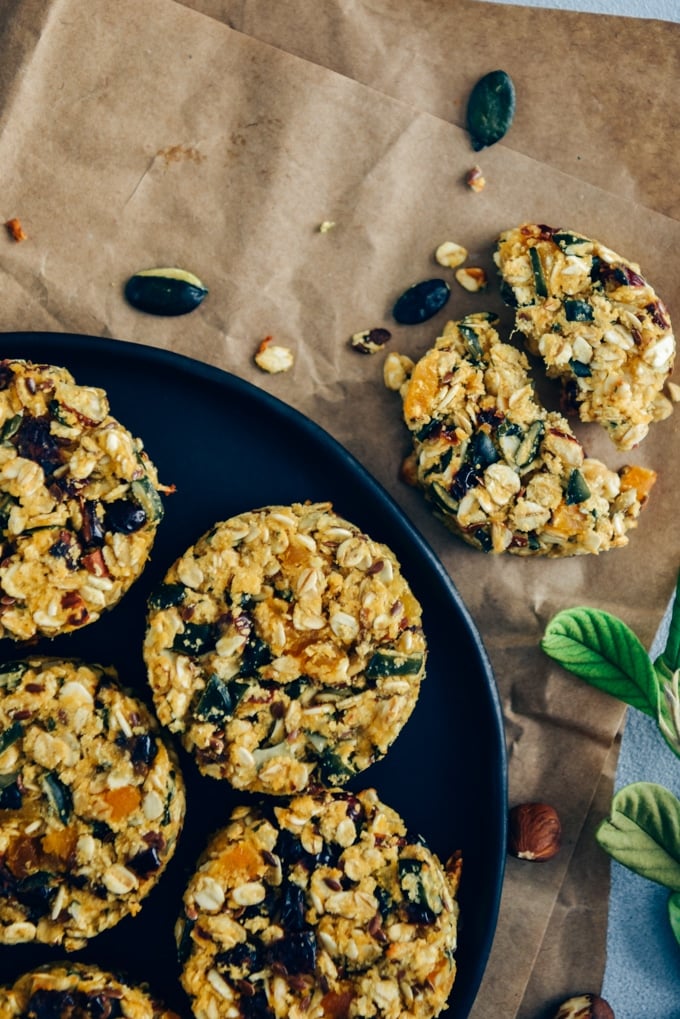 Pumpkin breakfast cookies with dried apricots, cranberries and nuts served on a black plate.