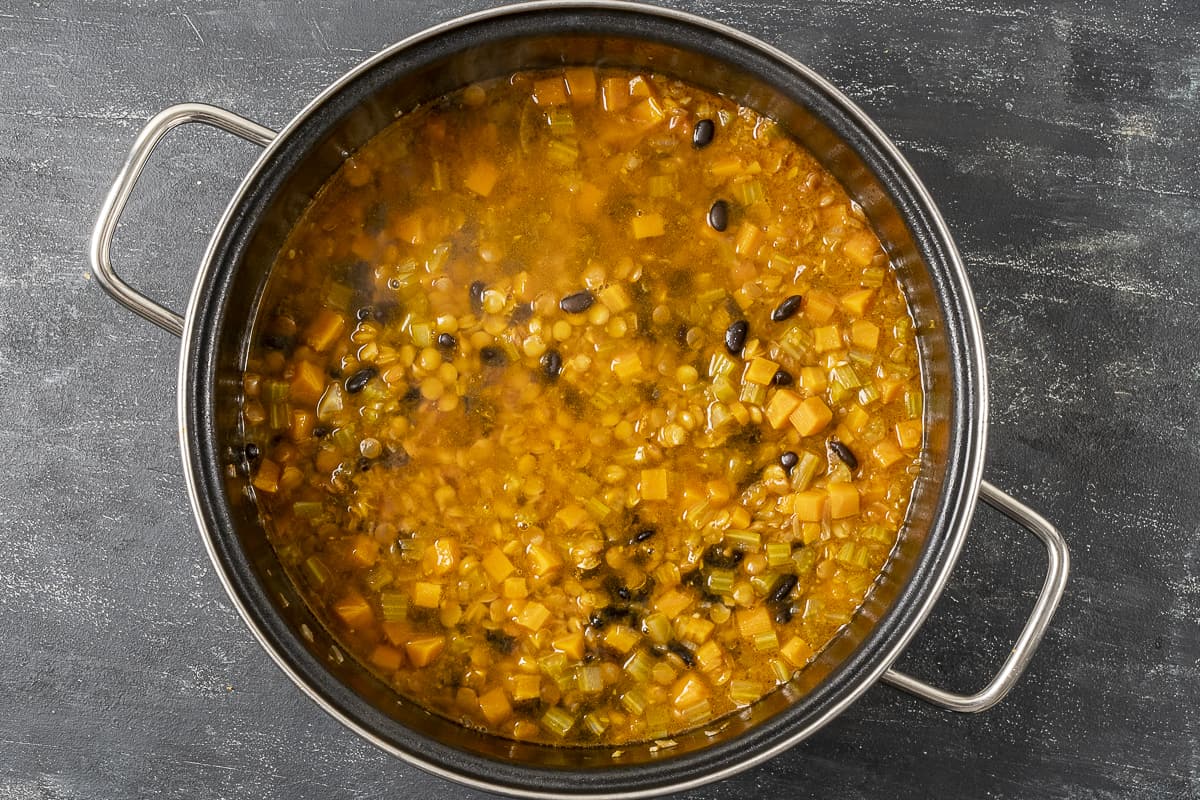 Green lentils, black beans and vegetables in a pan.