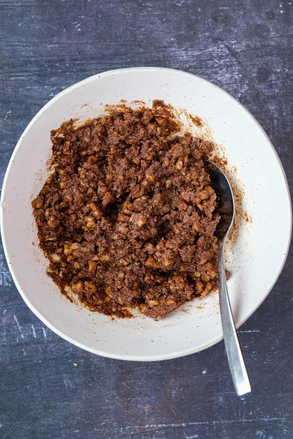 Filling with butter, nuts and pumpkin spice in a white bowl and a spoon inside it.