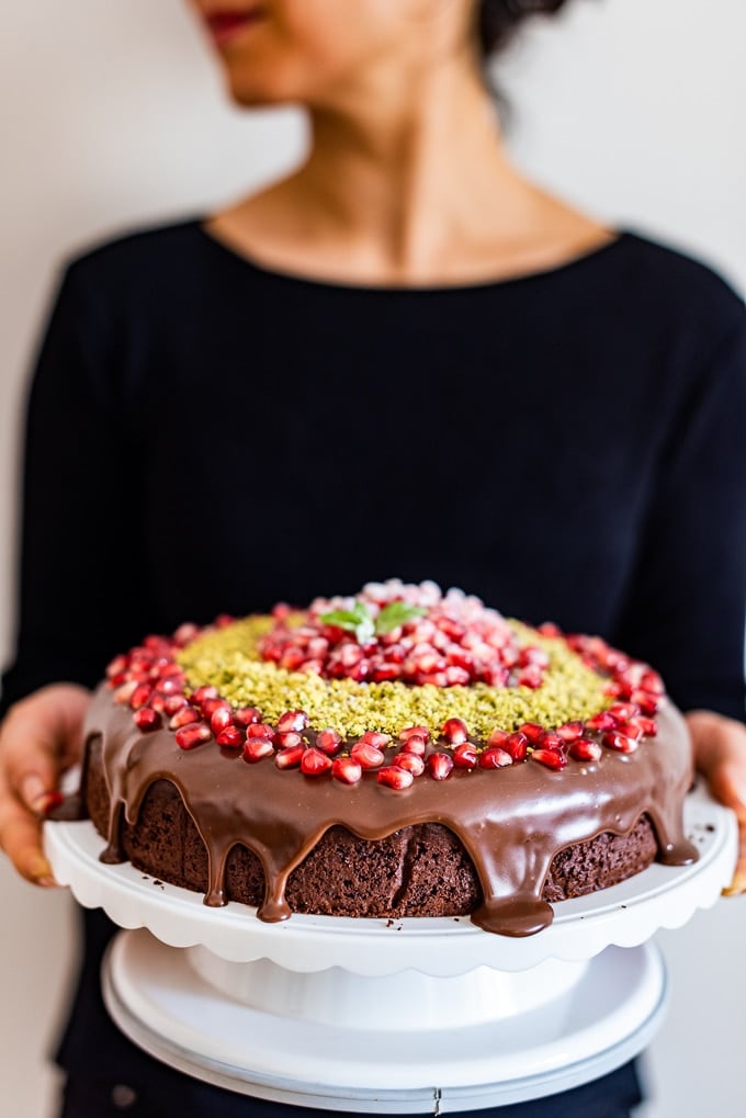 Woman holding a Christmas cake placed on a cake stand.