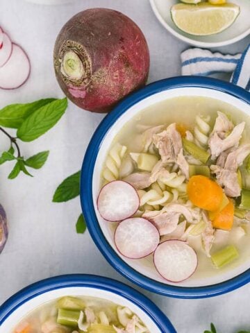 Chicken noodle soup with winter vegetables in white bowls