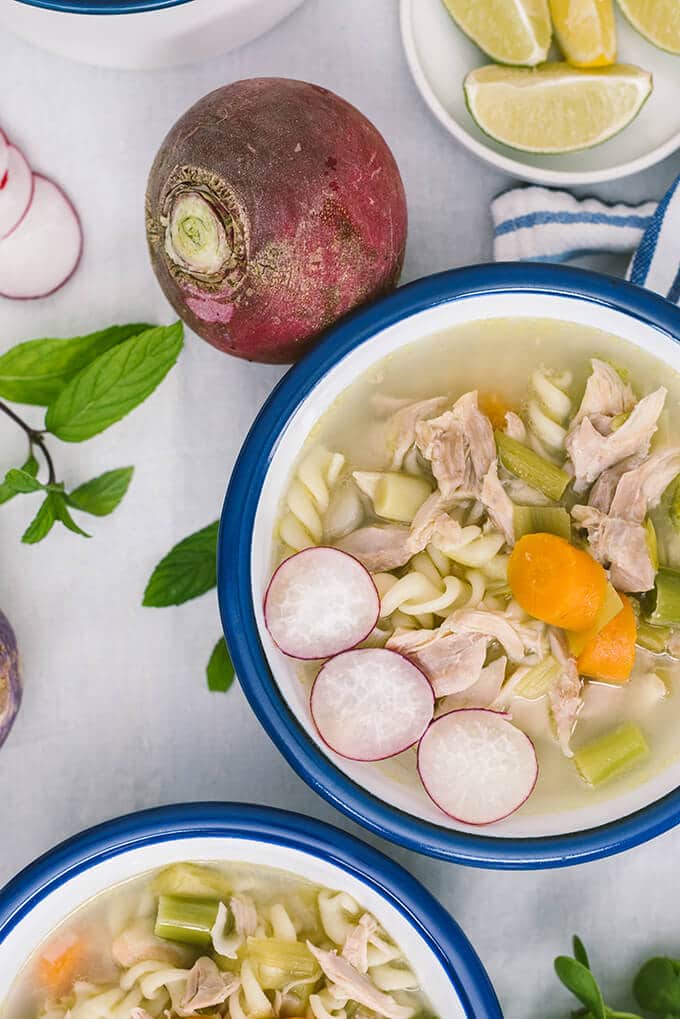 Chicken noodle soup with winter vegetables in white bowls