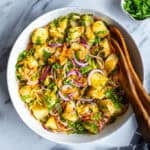 Turkish potato salad in large bowl and wooden spoons inside it.