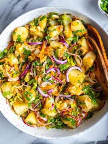 Turkish potato salad in large bowl and wooden spoons inside it.