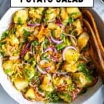 Turkish potato salad with boiled potatoes, red onion, grated carrot, fresh herbs, and olive oil dressing in a large bowl.