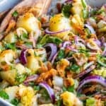 Turkish potato salad with boiled potatoes, red onion, grated carrot, parsley, and olive oil dressing in a bowl.