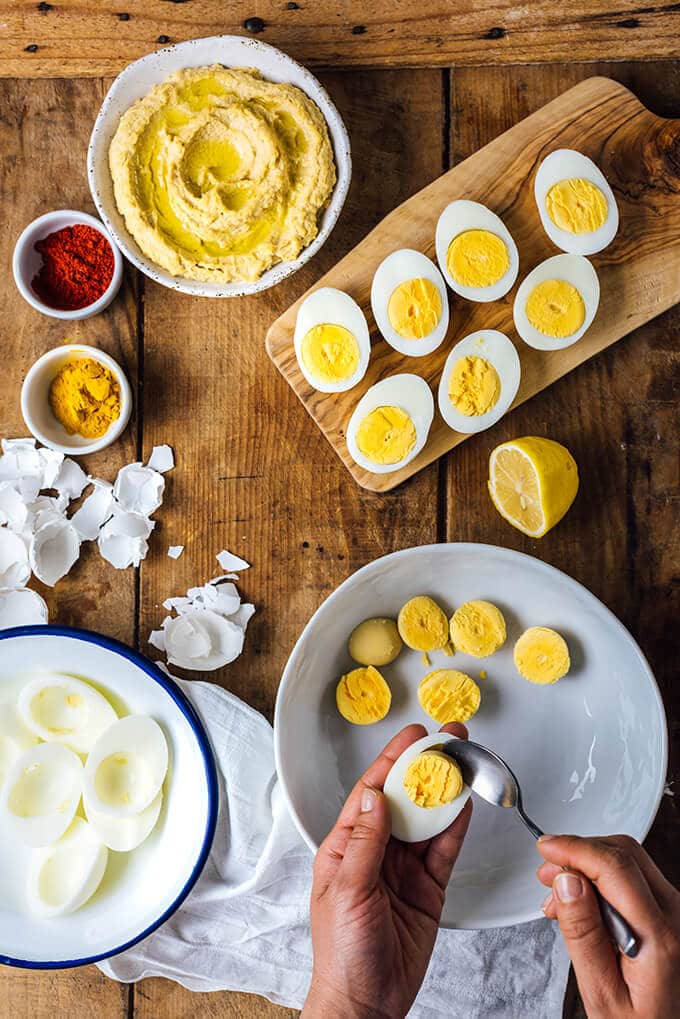 Removing yolks from hard boiled eggs to make deviled eggs with hummus. 