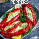 Feta stuffed red peppers garnished with fresh dill and lemon slices on an oval plate.