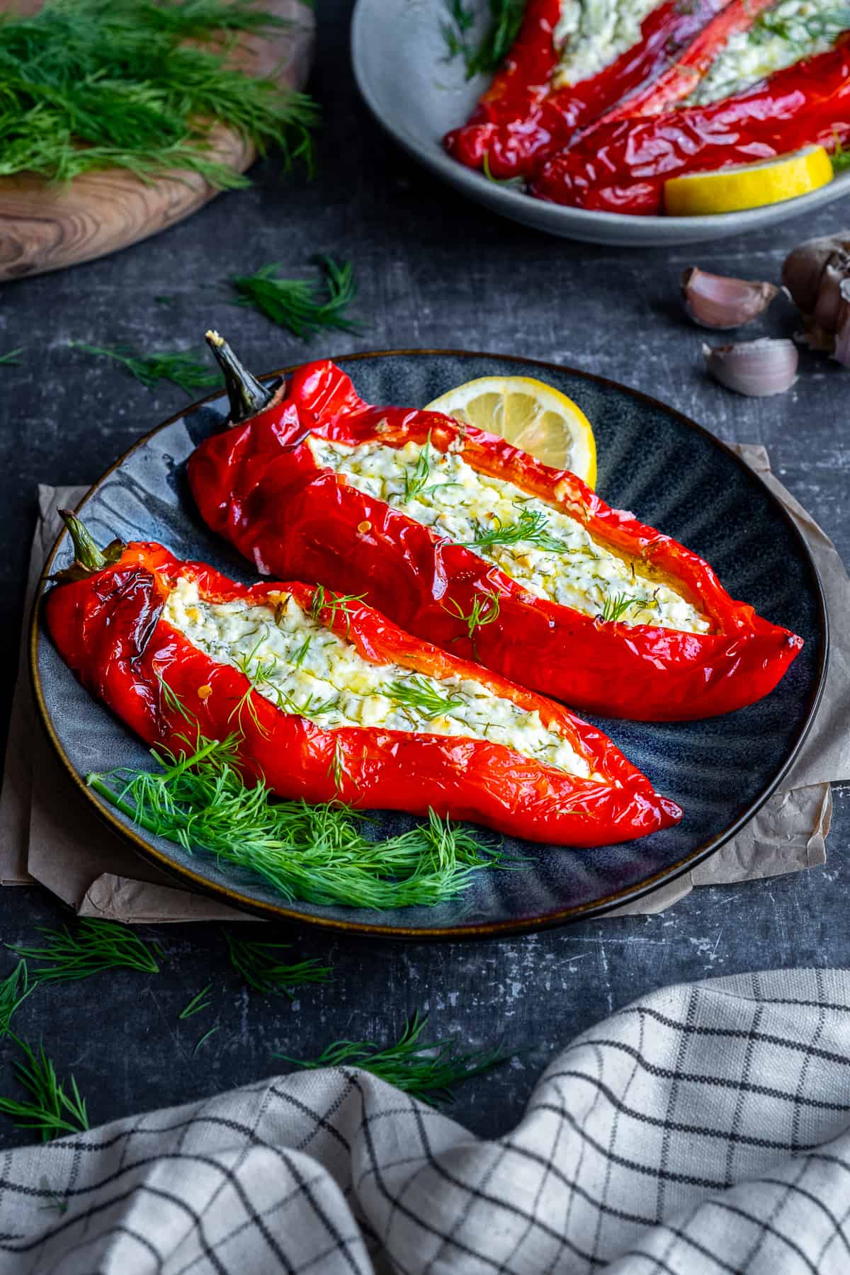 Peppers stuffed with feta cheese garnished with fresh dill and a slice of lemon on