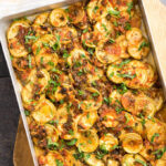 Zucchini and tomato casserole topped with herbs in a baking pan.