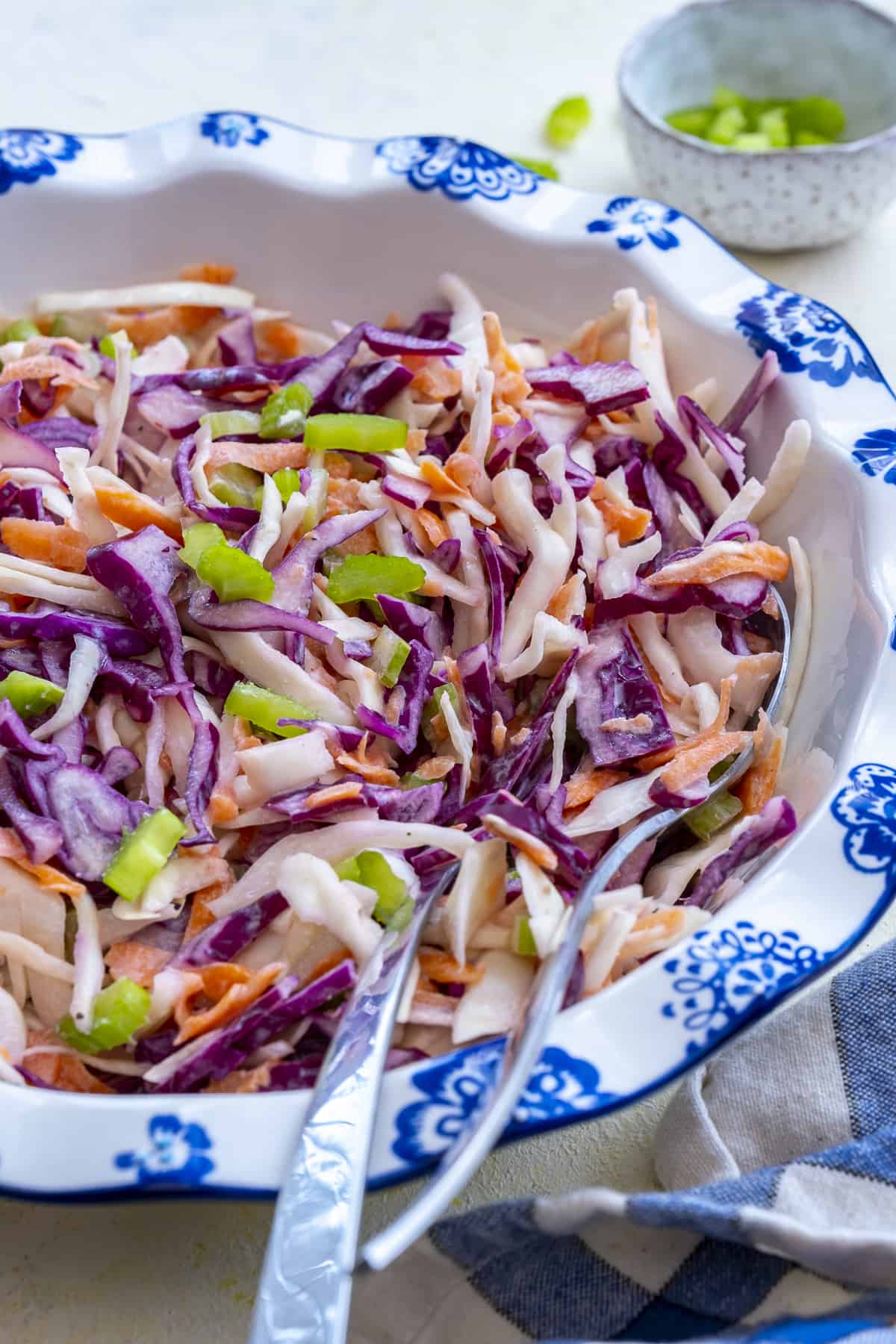Coleslaw garnished with diced celery in a white bowl.