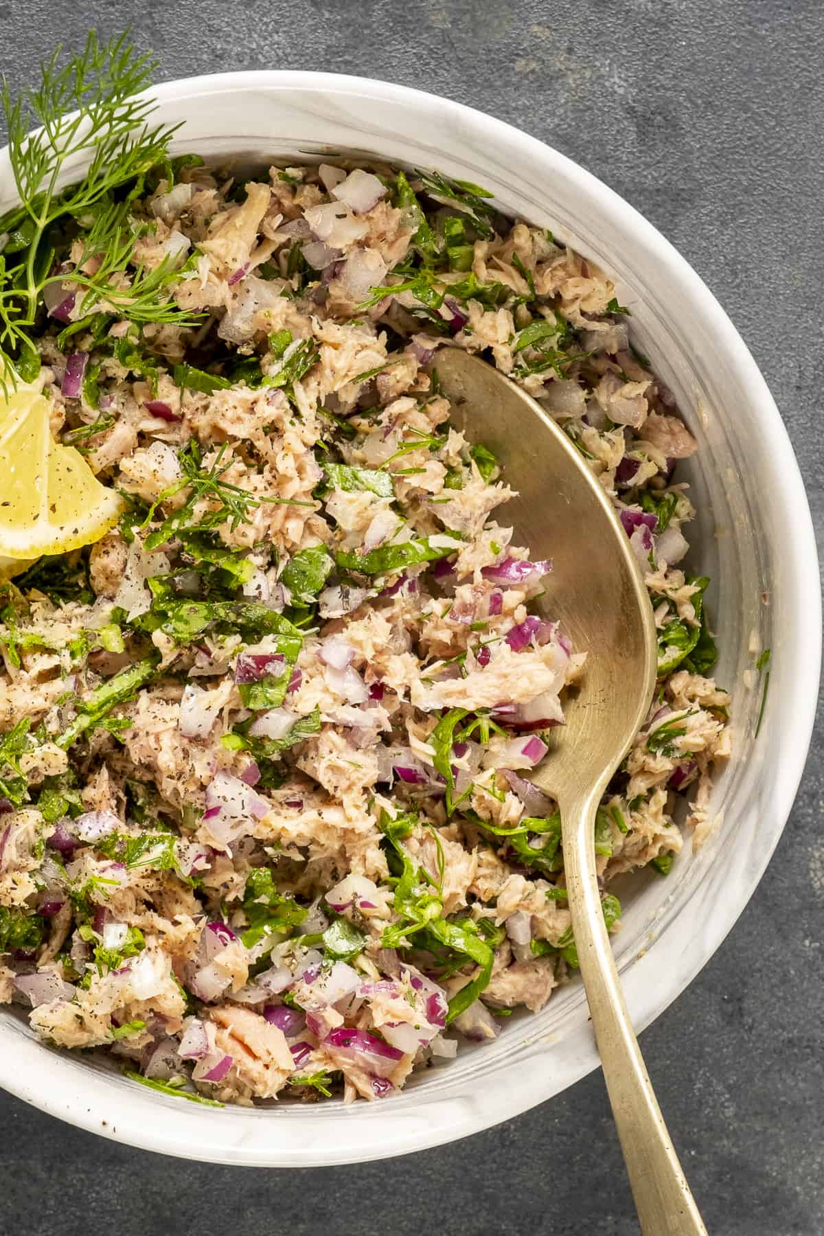 Tuna salad in a white bowl and a spoon in it.