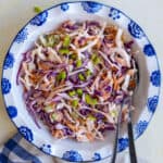 Healthy coleslaw in a white bowl and spoons inside it.
