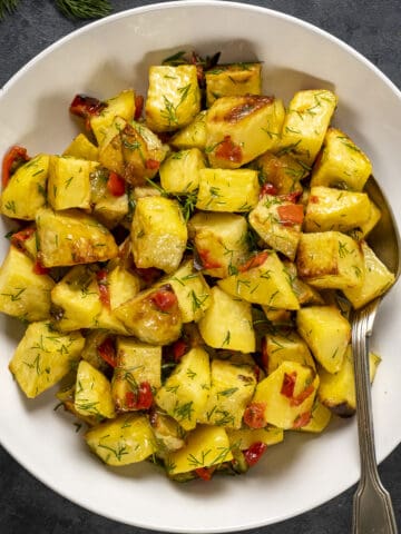 Lemon garlic potatoes in a white bowl and a spoon in it.