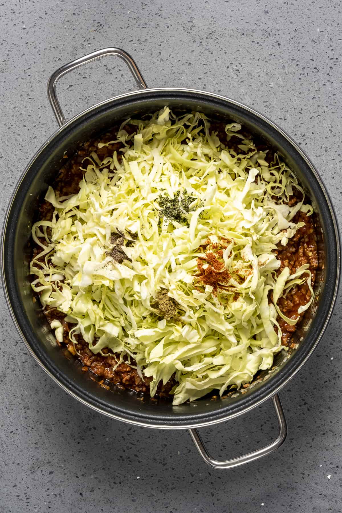 Shredded cabbage, spices and ground beef in a large pot.