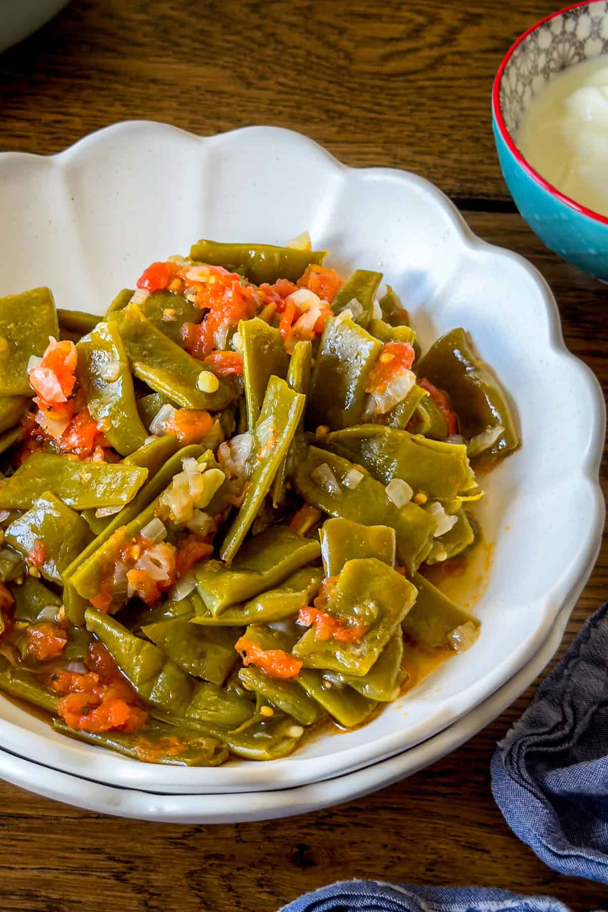 Turkish green beans (zeytinyagli taze fasulye) cooked with olive oil, tomatoes, and onions, served in a white bowl.