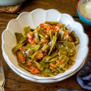 Turkish green beans with tomatoes and onions served in a white bowl.