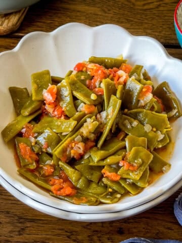 Turkish green beans with tomatoes and onions served in a white bowl.