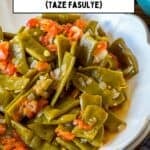 Turkish green beans (taze fasulye) with tomatoes and onions, served in a white bowl, with a text overlay and website link.