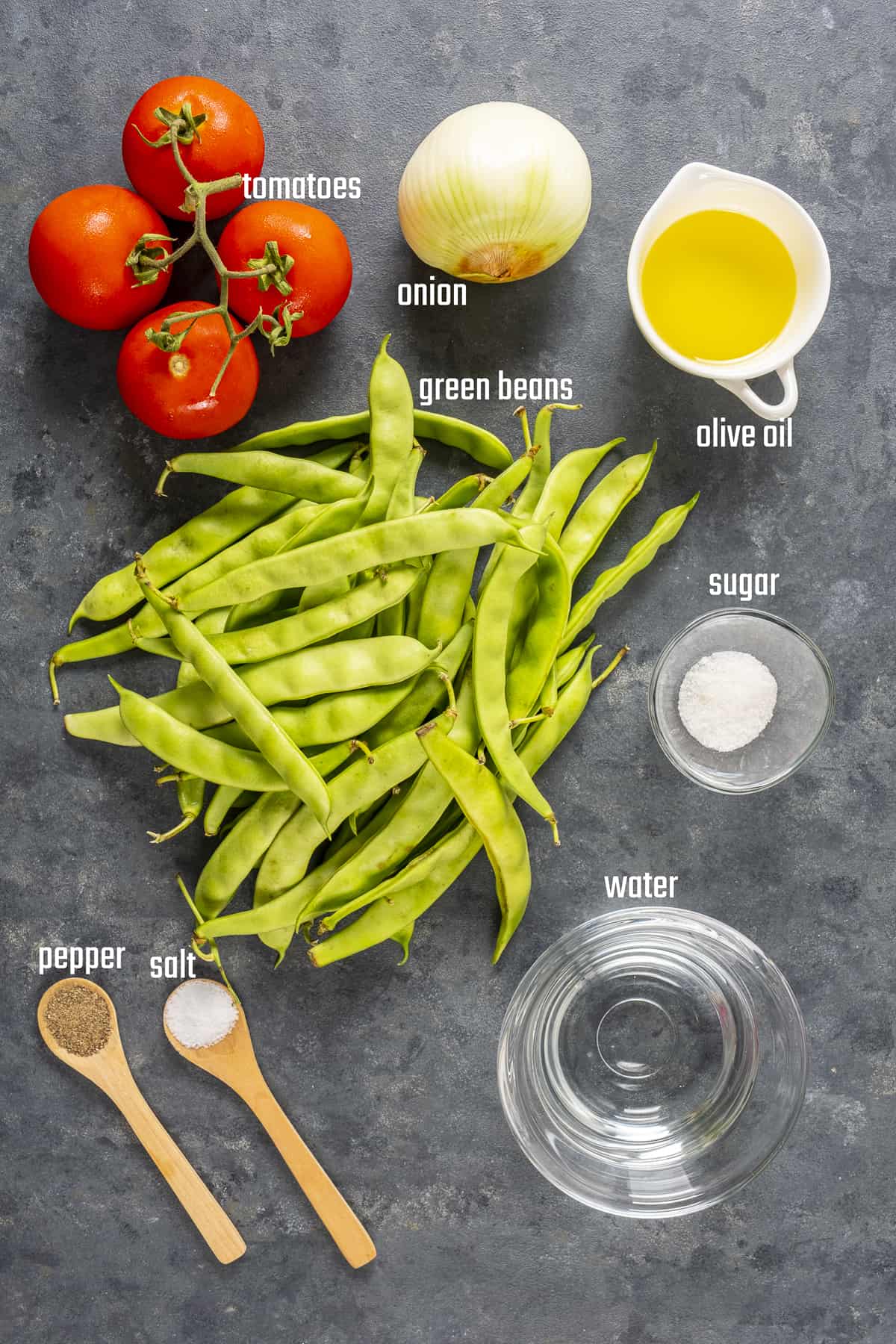 Green beans, tomatoes, onion, olive oil, sugar, salt and pepper and water on a dark background.