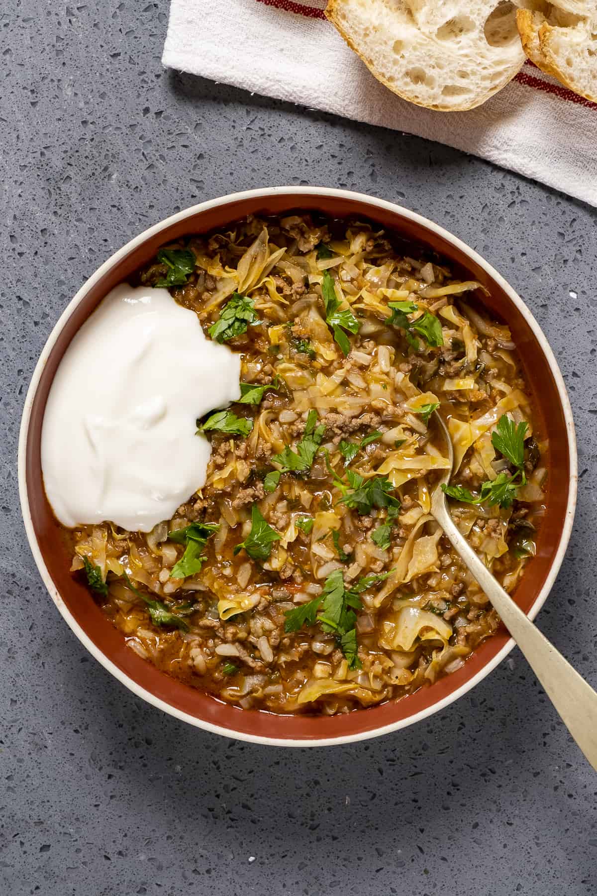 Cabbage roll soup topped with a little yogurt and parsley in a bowl.