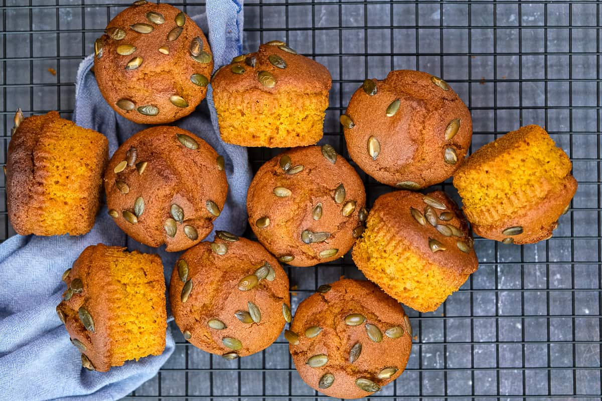 Cornbread muffins with pumpkin seeds cooling on a rack.