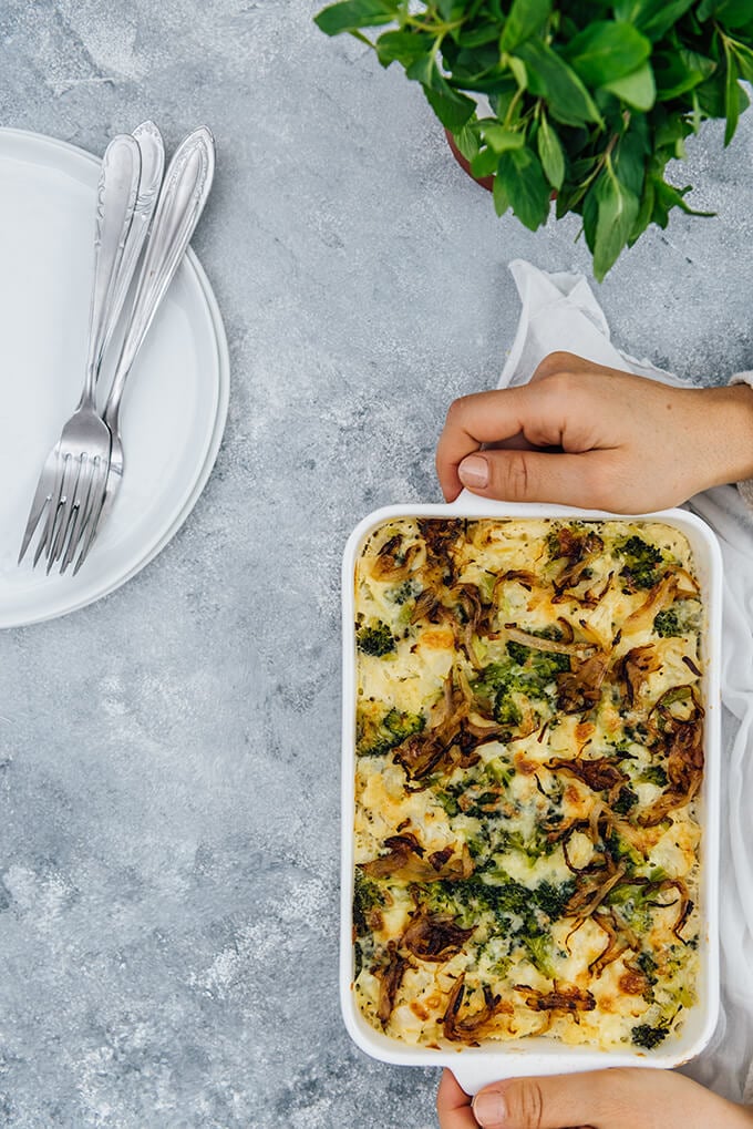 Holding a gluten-free and low-carb broccoli and cauliflower side dish in a baking pan