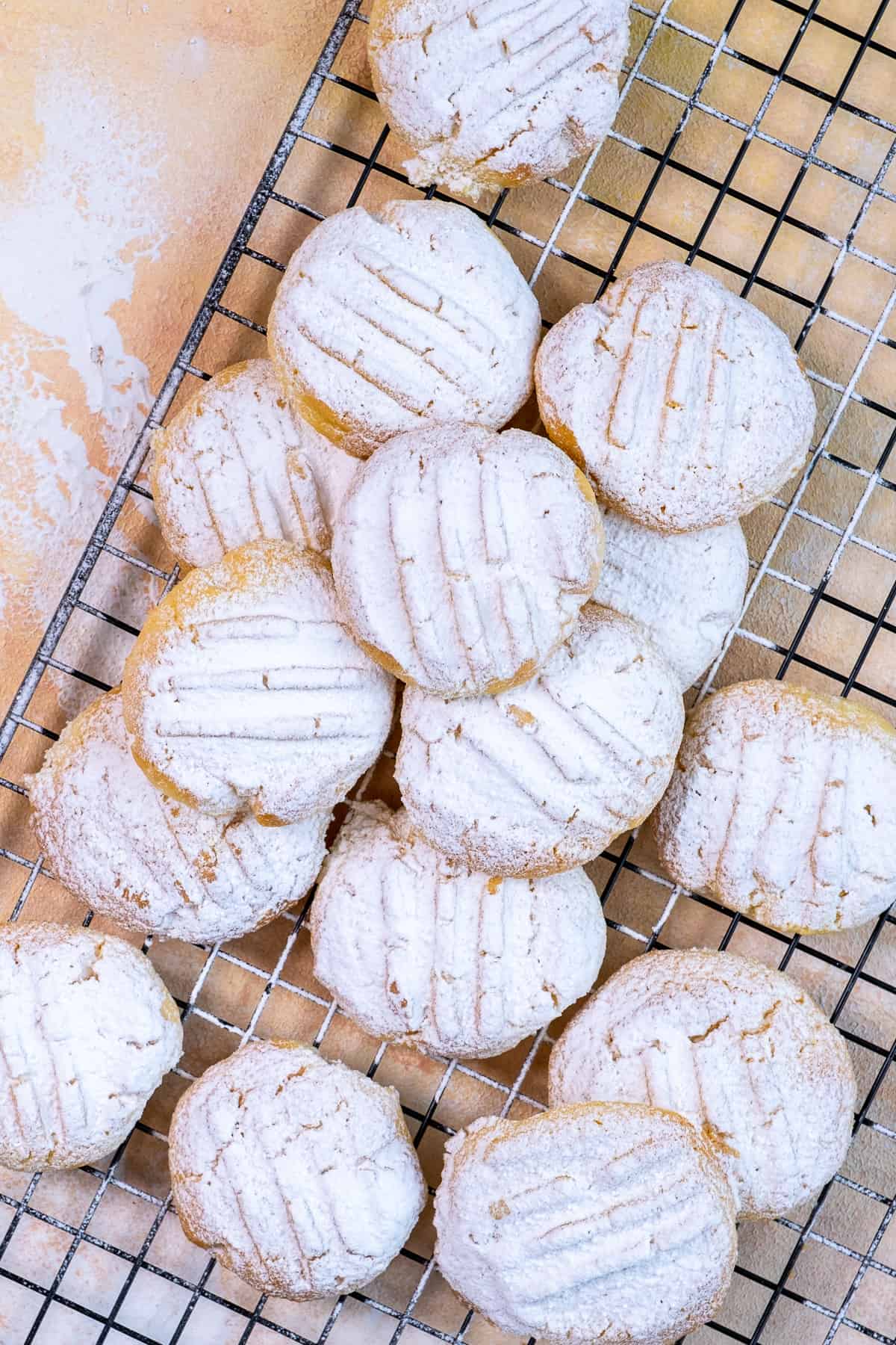 Cookies topped with powdered sugar on a cooling rack.